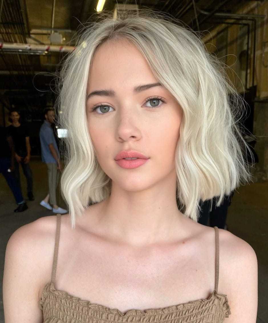 Young woman with short blonde hair in a dimly lit industrial setting.